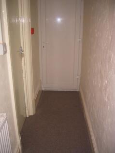 A narrow indoor hallway with textured cream wal...