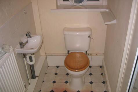 Compact restroom featuring a white toilet with ...