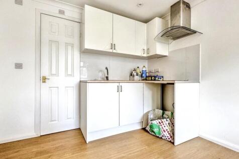 A modern and tidy kitchenette featuring white c...