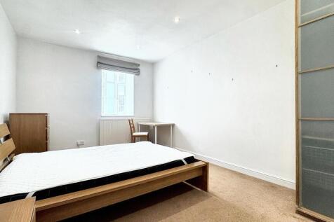 A bright, clean double bedroom featuring a wood...