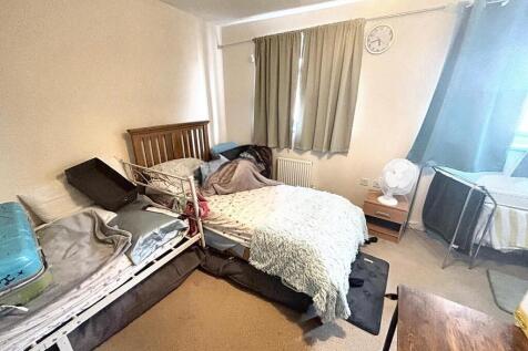 A modest single bedroom featuring a bed with be...