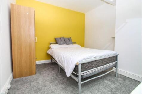 A cozy single bedroom featuring a bright yellow...