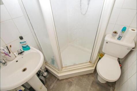 A compact bathroom featuring a corner shower wi...