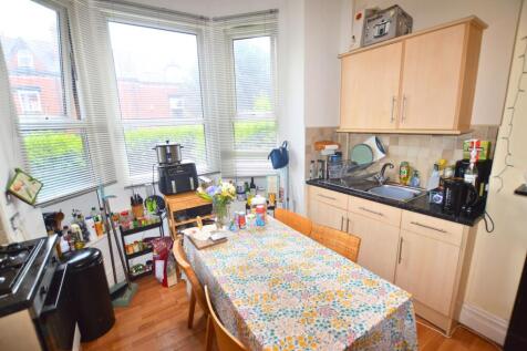 A bright kitchen featuring a floral tablecloth-...