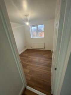A small, neat bedroom featuring clean wood-effe...