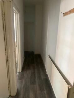 A narrow hallway featuring clean wooden floorin...