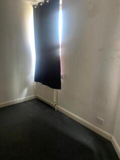 A small bedroom with dark curtains partially co...