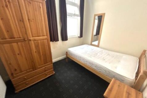 A tidy single bedroom featuring a wooden bed fr...