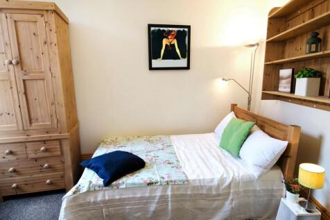 A cozy single bedroom featuring a comfortable b...