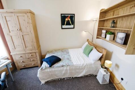 A cozy and tidy single bedroom featuring a wood...