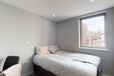 A cozy single bedroom featuring a neatly made b...