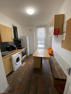 A compact kitchen featuring wooden cabinetry, a...