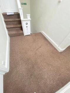 A carpeted staircase area with white walls and ...