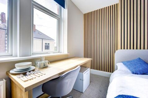 A bright, neatly arranged single bedroom featur...
