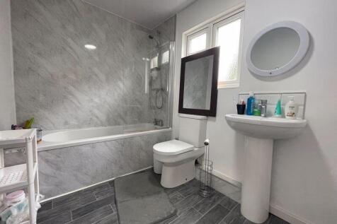 A modern bathroom suite featuring a marble-effe...