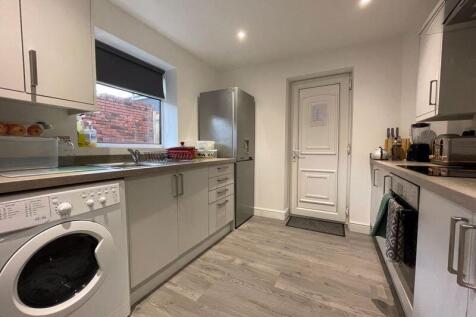 A modern kitchen featuring light grey cabinets,...