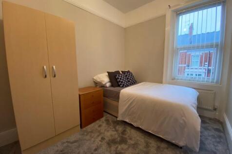 A neat and cozy bedroom featuring a single bed ...