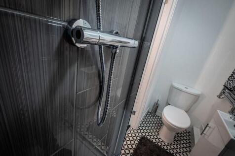 A modern bathroom featuring a glass-enclosed sh...