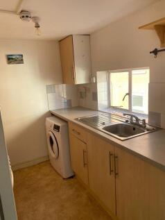 A compact kitchen space featuring light wood ca...