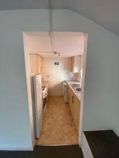 Compact galley kitchen featuring light wood cab...