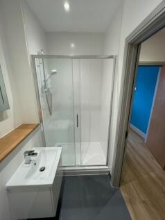 A modern bathroom featuring a clean glass-enclo...