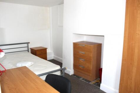 A tidy single bedroom with white walls, a woode...