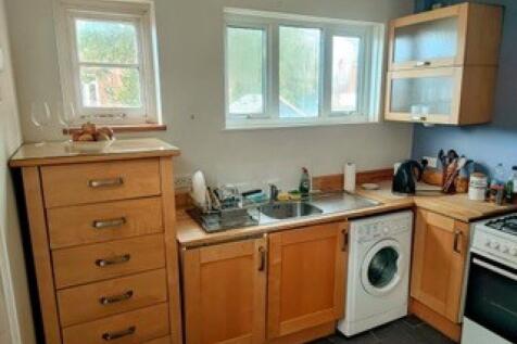 A bright kitchen with wooden cabinetry, a washi...