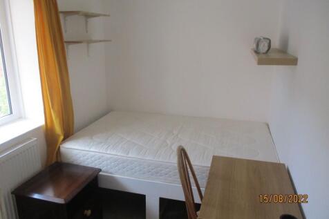A simple and tidy bedroom featuring a comfortab...