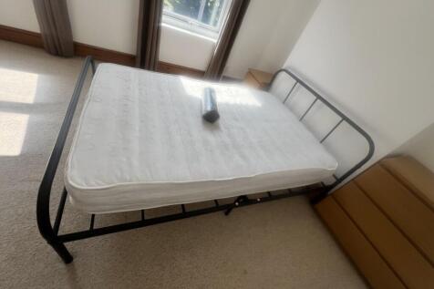 A bright single bedroom featuring a metal frame...