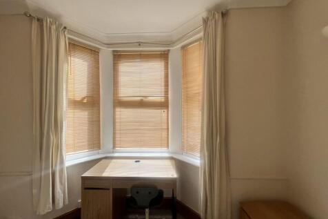 A cozy single bedroom featuring a large bay win...