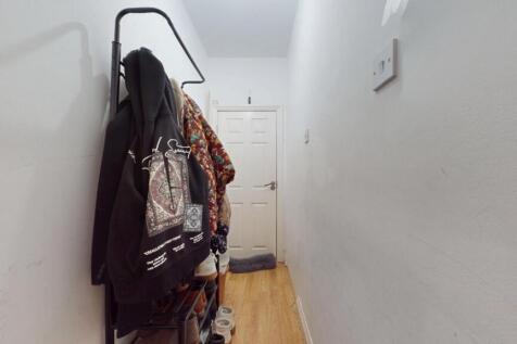 A narrow hallway with wooden flooring and white...