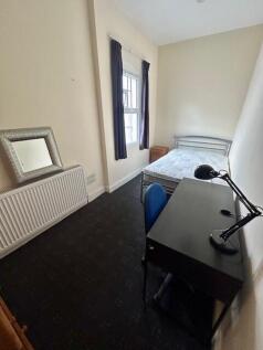 A neat and tidy single bedroom featuring a sing...