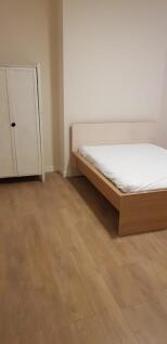 A simple and neat bedroom featuring a wooden be...