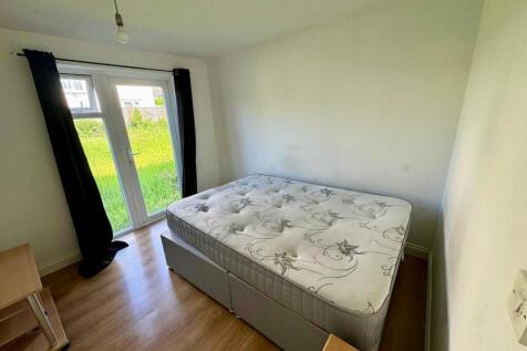 A bright double bedroom featuring a large windo...