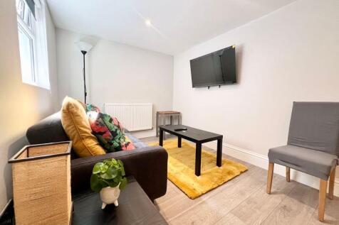 A bright and tidy living room featuring a comfo...