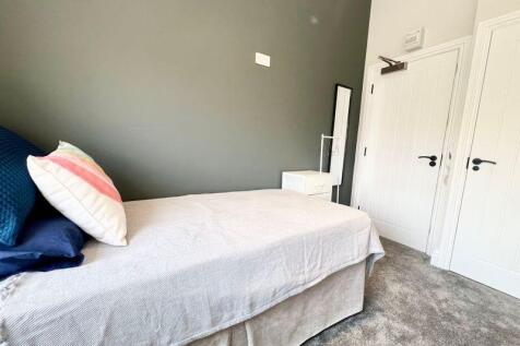 A cozy single bedroom featuring a neatly made b...