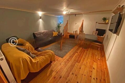 A cozy living room featuring warm wooden floori...