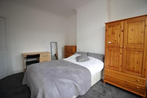 A cozy single bedroom featuring a neatly made b...