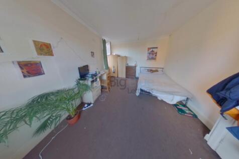 A narrow and tidy room with a single bed, desk,...