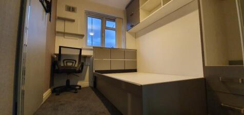 A compact single bedroom featuring a built-in b...