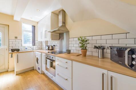 A bright, modern kitchen featuring white cabine...