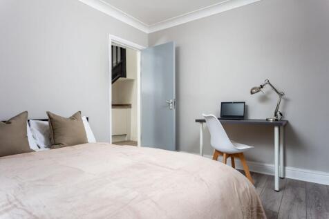 A cozy double bedroom featuring a soft beige be...