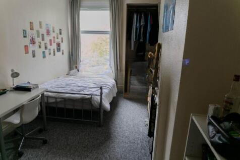 A compact bedroom featuring a single bed by a l...
