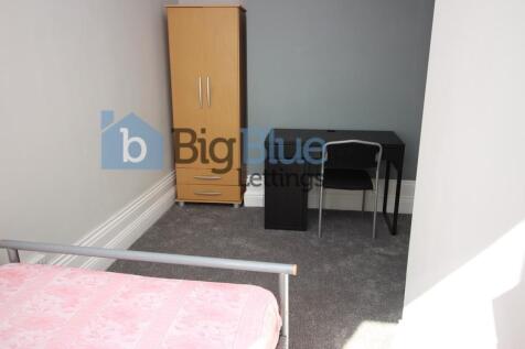A tidy single bedroom featuring a bed with a so...
