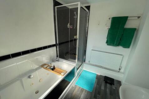 Bright and clean bathroom suite featuring a lar...