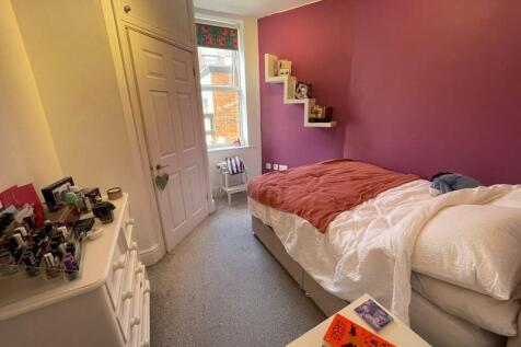 A cozy single bedroom featuring a comfortable b...