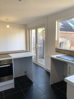 A bright kitchen featuring modern black tiled f...