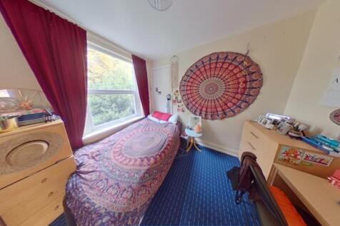 A brightly lit single bedroom featuring a cozy ...