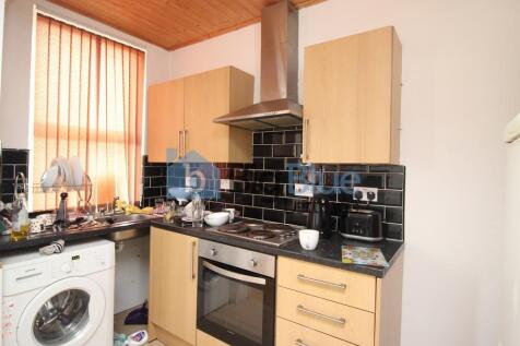 A compact kitchen featuring light wood cabinetr...