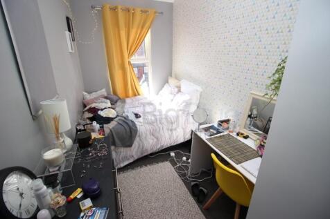 A cozy single bedroom featuring a bed with brig...